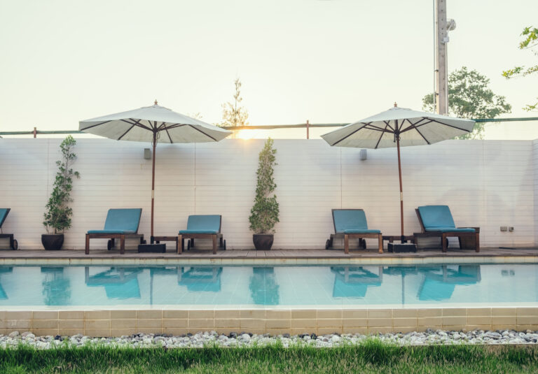 Blue sunbed with white umbrella on swimming pool